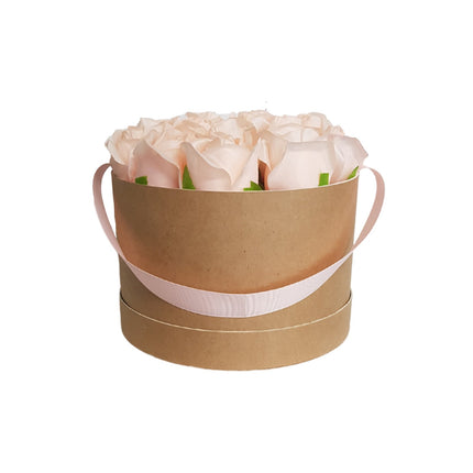 Blush coloured artificial roses in a cardboard hatbox with a decorative ribbon handle